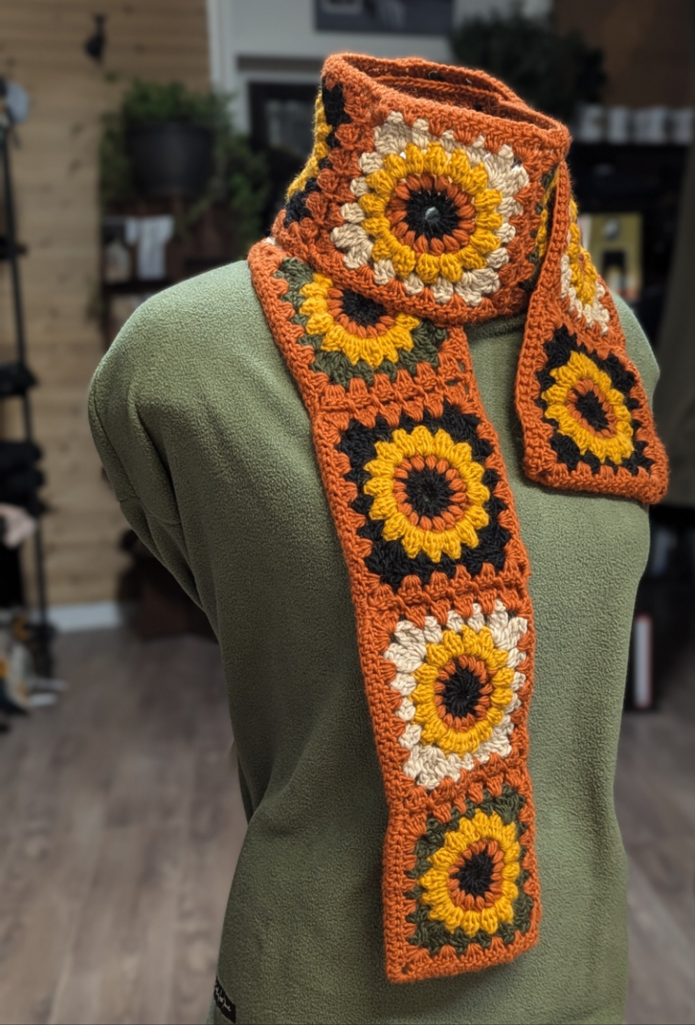 Crochet Scarf. Sunflowers on black, white, and green with orange trim